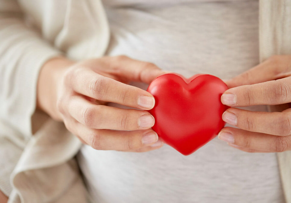 close up of pregnant woman with red heart
