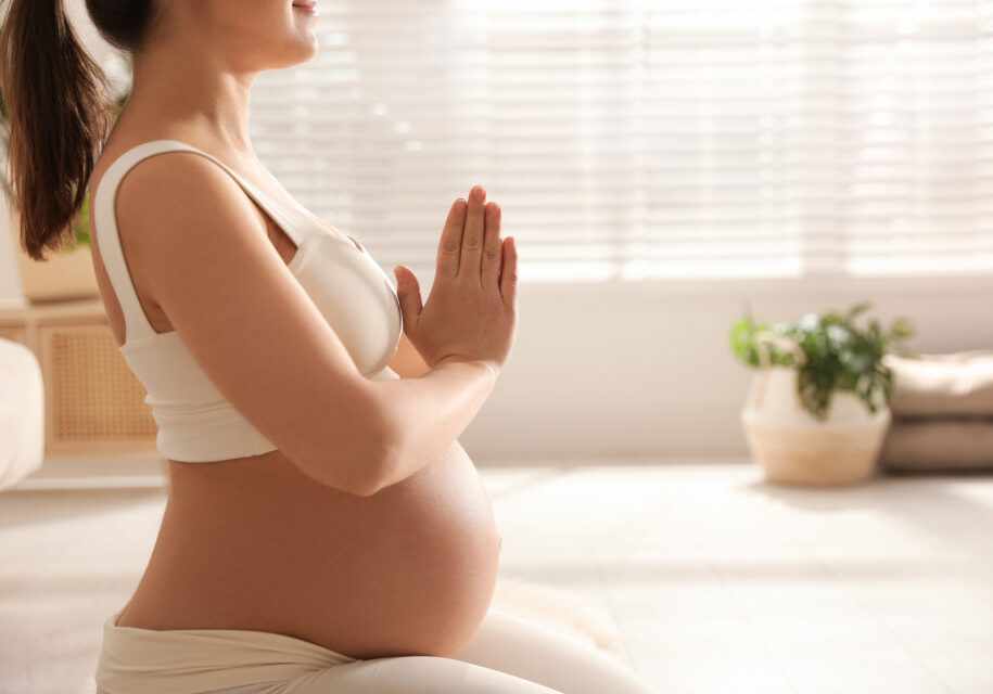 Young pregnant woman practicing yoga at home, closeup. Space for text